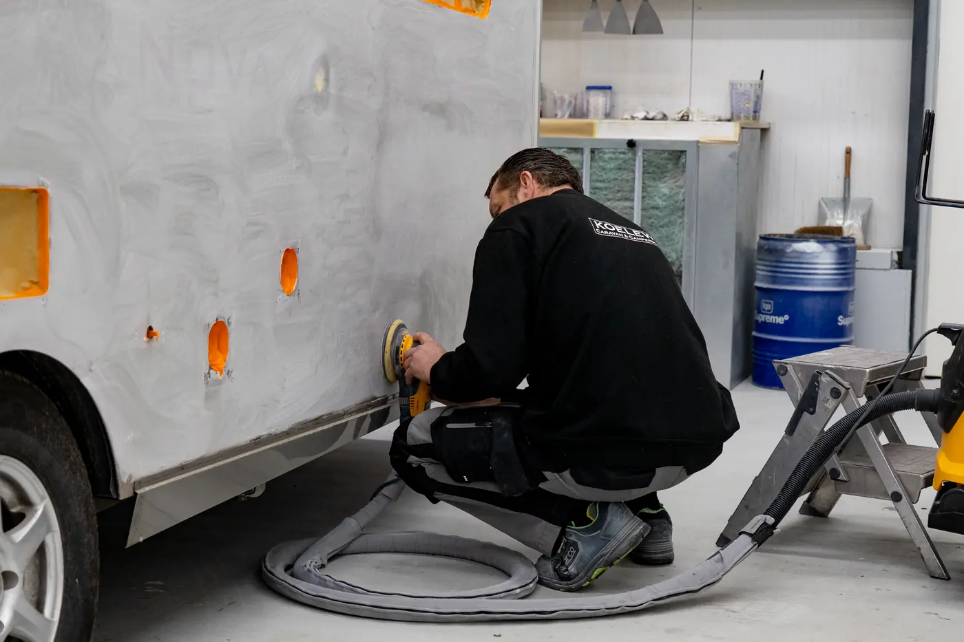 Monteur schuurt een herstelde caravanwand